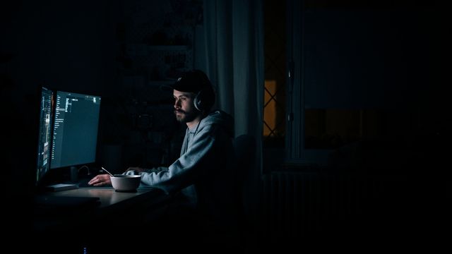 A man sits working at his computer late at night. 
