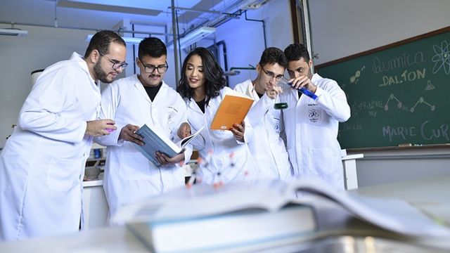 Group of people in lab coats brushing up on their scientific knowledge. 