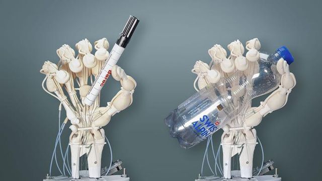 Two robotic hands holding a pen and a water bottle. 